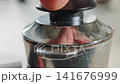 Tamping coffee grounds in portafilter for espresso machine 141676999
