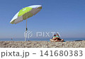 Relaxing woman on beach near calm sea. 141680383