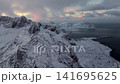 Snowy coastal mountains and fjord at sunrise with scattered islets 141695625