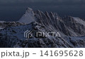 Snow covered jagged mountain ridge under moody overcast sky at dawn 141695628