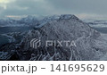 Snow overed mountain peak emerging through low clouds 141695629
