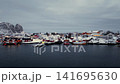 Snowy coastal village beside a quiet harbor 141695630