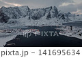 Aerial view of snowy fishing village in a fjord with surrounding mountains 141695634