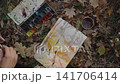 The artist paints a forest landscape on the ground among fallen autumn leaves 141706414