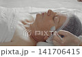 Cosmetologist applies a rejuvenating mask on the face of an elderly woman 141706415