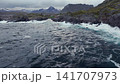 Aerial view of rocky coastal village with choppy sea and overcast sky 141707973