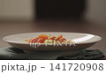 Slow motion making pesto penne pasta with mozzarella and tomatoes in deep plate closeup 141720908