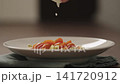 Slow motion making pesto penne pasta with mozzarella and tomatoes in deep plate closeup 141720912