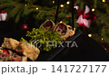 Person picking up tempura sushi roll with tuna and strawberry using chopsticks from a black slate plate during a christmas holiday dinner in a japanese restaurant 141727177