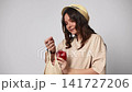 Young smiling woman putting fresh red pepper in a reusable string shopping bag isolated on a white background 141727206