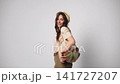 Joyful woman in safari outfit carrying reusable mesh bag with fresh vegetables isolated on white background 141727207