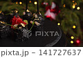 Black sushi roll with caviar and gold leaf being picked up with chopsticks during Christmas dinner, showcasing Japanese cuisine and gourmet seafood in a festive setting 141727637