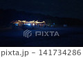 Blurred night gathering with glowing string lights over outdoor venue and dark sky 141734286
