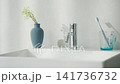 A woman picks up cosmetics from the bathroom sink. 141736732