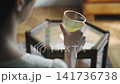 A woman picks up a cup of tea. 141736738