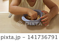 テーブルでボウルからシリアルをつまんで食べる子供の手元 141736791