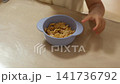 テーブルでボウルからシリアルをつまんで食べる子供の手元 141736792