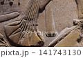 Extreme closeup of ancient Egyptian sandstone relief carving showing pharaoh profile face with crown and collar. Detailed hieroglyphic wall. 141743130
