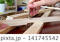 A woman's hand screws a hex screw into a wooden panel. 141745542