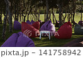 A seating area of soft seats is located in the shade of pine trees in the park 141758942