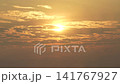 Bright morning sun shining through layered clouds in a warm golden sky. 141767927