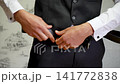 Groom Man Adjusting Black leather Belt with Elegant White Shirt and Tailored Trousers. 141772838