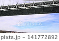 Verrazzano Narrows suspension bridge view from water sailing past steel construction tower near Fort Wadsworth in New York harbor under cloudy blue sky 141772892