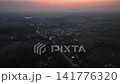 Tiny street lights and house lamps glow brightly across a quiet rural village in Nong Bua Lamphu during dusk. 141776320