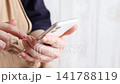 A woman in an apron operates a smartphone. 141788119