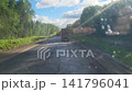 We follow a logging truck on the road that is being repaired. We pass a large number of construction vehicles laying asphalt. 141796041