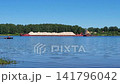 A small tugboat pushing a heavy cargo barge down a spring river. 141796042