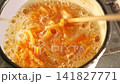 Candied orange peels simmering in pot, chopstick stirring glossy citrus strips in bubbling sugar syrup. warm kitchen light. Smallbatch handmade confection process, sticky caramelizing. Citrus sweets 141827771