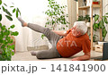 Happy smiling mature senior man doing exercises of gymnastics at home. Concept of healthy lifestyle, fitness, recreation, well being. Elderly male exercising training, stretching. Old man working out 141841900