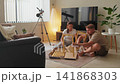 Couple sitting on the floor in their living room assembling furniture 141868303