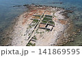 Aerial drone shot of the ancient Sipar archaeological site featuring historical ruins on a narrow rocky peninsula surrounded by the clear blue sea in Istria, Croatia. 141869595