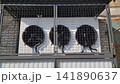 Fans working on the wall in a box behind a grate 141890637
