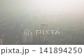 View from a drone during the day of a city shrouded in smoke from summer forest fires 141894250