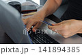 Focused work scene. Person verifying bill with laptop. Individual handling documents and digital payment processing. Someone reviewing bills and utilizing computer with coffee close by 141894385