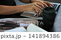 Focus on hands drafting alongside hot beverage. Person engaged in digital and traditional planning tasks. Individual meticulously working on computer and jotting notes with coffee nearby 141894386