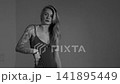 Blonde with a beautiful figure in a black bodysuit poses in the studio. Studio lighting, low exposure, monochrome light. 141895449