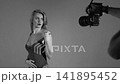 Blonde with a beautiful figure in a black bodysuit poses in the studio. Studio lighting, low exposure, monochrome light. 141895452