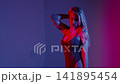 A blonde with a beautiful figure poses in a black bodysuit in a studio. Studio lighting, low exposure, neon. 141895454