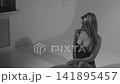 Blonde with a beautiful figure in a black bodysuit poses in the studio. Studio lighting, low exposure, monochrome light. 141895457