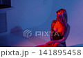 A blonde with a beautiful figure poses in a black bodysuit in a studio. Studio lighting, low exposure, neon. 141895458