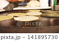 Mexican cook preparing handmade corn tortillas on a comal 141895730