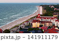 Drone view Ostseebad Kuhlungsborn resort, Baltic beach, promenade, Ferris wheel, hotels, and red roofs at dusk. Calm coastline, beach chairs, seaside tourism, and summer mood shape scenic cityscape 141911179