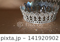 Golden Royal Crown with Sparkling Light Reflections on Beige Fabric Background 141920902