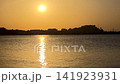 Continuous time lapse of a vibrant golden sunset with the sun dipping behind the silhouette of Denia castle and port. Smooth water reflection with sun trail turning from bright orange to deep dusk red 141923931