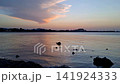 Beautiful 4K time lapse of dusk afterglow sky over Denia port and castle silhouette. Vibrant gradient from orange horizon to deep purple and blue night sky with flashing marina city lights and quiet  141924333