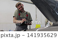 Mechanic calls customers for communication, in the car service center. Concept repair of machines fault diagnosis repair specialist, technical maintenance on-board computer. 141935629